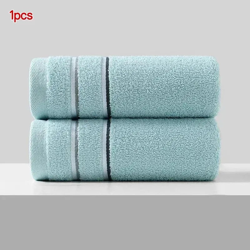 A stack of light blue, textured face towels with black stripes.