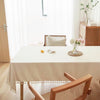 A light beige table is set with textured cotton tassel runners in a bright, modern room.