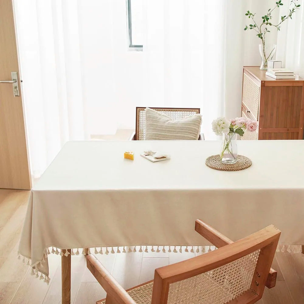 A light beige table is set with textured cotton tassel runners in a bright, modern room.