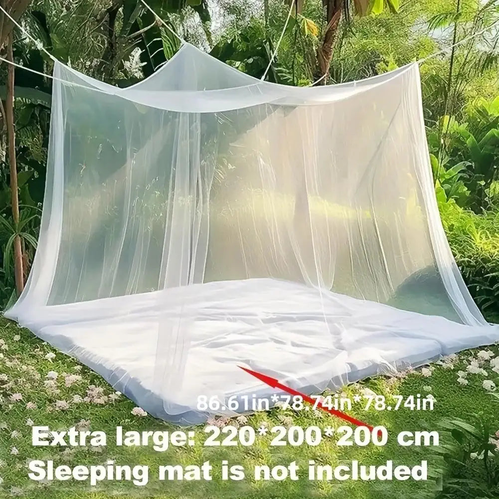 A large white mosquito net is draped over a frame outdoors, used as a sleeping mat or shade.