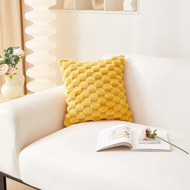 A bright yellow honeycomb patterned plush pillow resting on a white sofa.