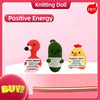 A knitted doll named Positive Energy featuring a flamingo, a green creature, and a yellow chick.