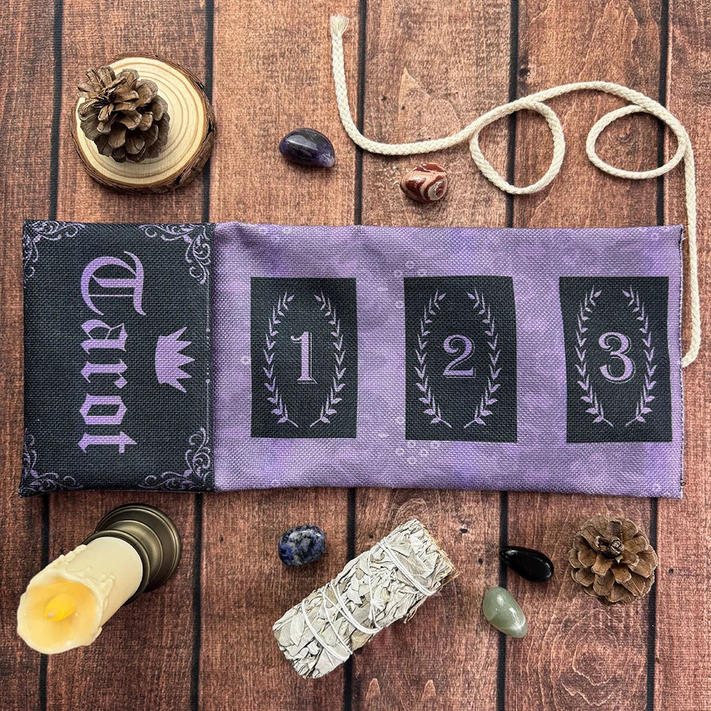 A purple fabric pouch for storing tarot cards, surrounded by pine cones, stones, and a tarot card.