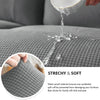 A close-up shows water dripping onto a gray fabric sofa seat, demonstrating the waterproof nature of the slipcover.