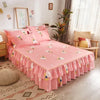 A pink double layer printed bed skirt with floral accents on a bed in a bright room.