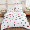 White duvet cover set with a red fruit print featuring apples and leaves on a bed.
