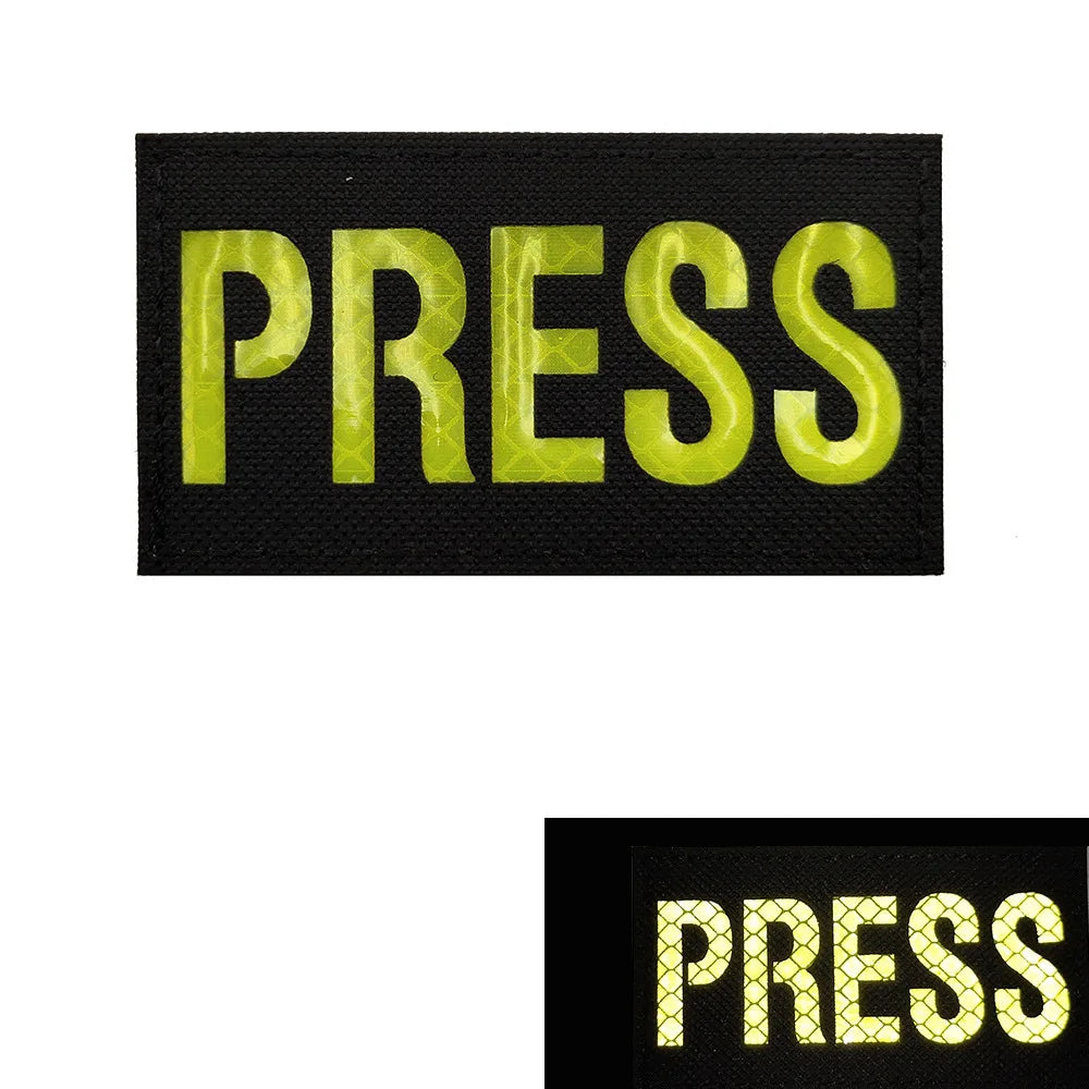 A black embroidered patch with the word PRESS in bright lime green text.