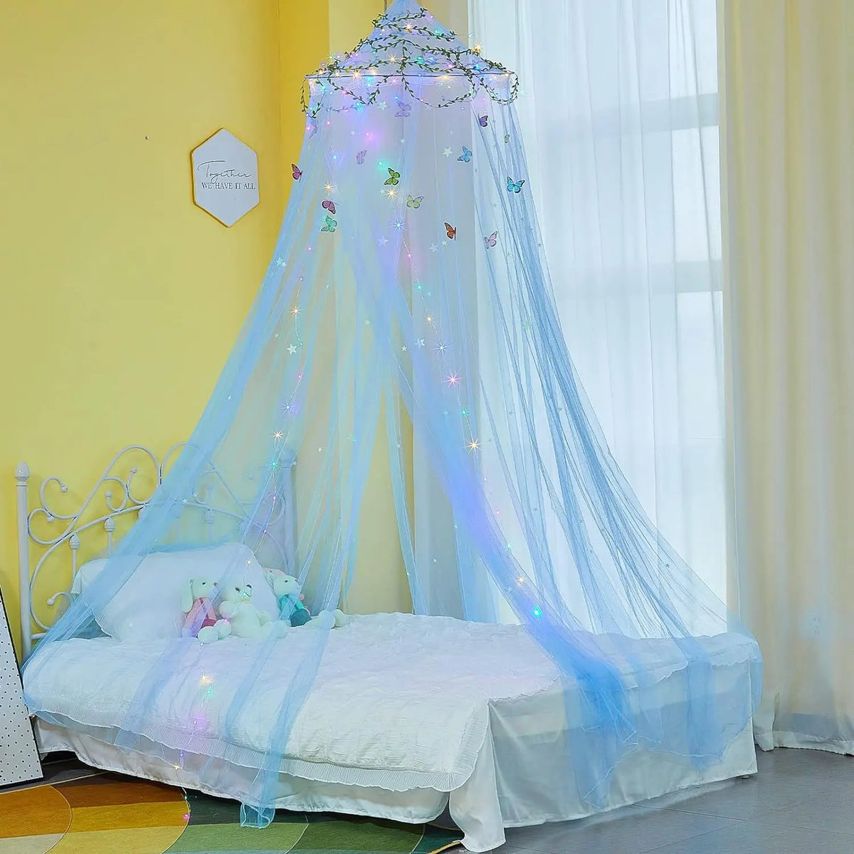 A decorative mosquito net bed curtain featuring light blue sheer fabric and sparkling accents in a bright room.