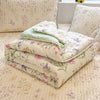 A stack of light green and floral patterned quilted blankets on a pink textured surface.