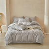 A light gray embossed leaf duvet cover set displayed on a bed in a softly lit room.
