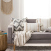 A collection of neutral-toned boho tufted throw pillow covers with tassels displayed on a gray sofa.