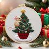 A hand embroidery kit featuring a festive Christmas tree decorated with red berries and gold accents.