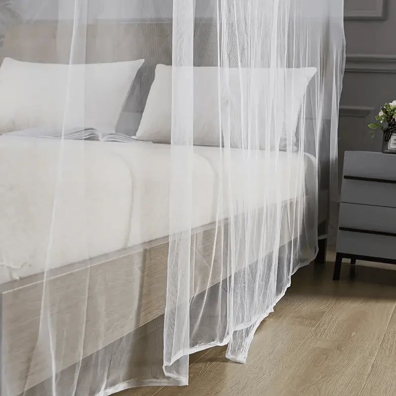 A sheer white mosquito net draped over a bed in a bedroom setting.