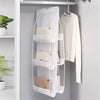 A white double-sided hanging closet organizer rack holding various bags and a shirt.