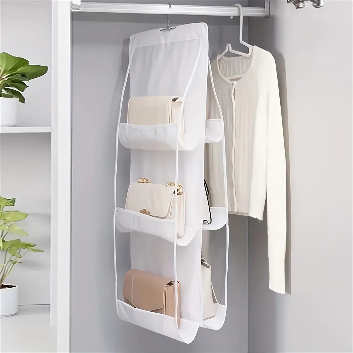 A white double-sided hanging closet organizer rack holding various bags and a shirt.
