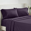 A purple striped bedding set featuring a duvet cover and pillows on a white upholstered bed.