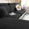 A dark gray thick jacquard sofa seat cushion cover with light gray pillows and a white decorative flower.