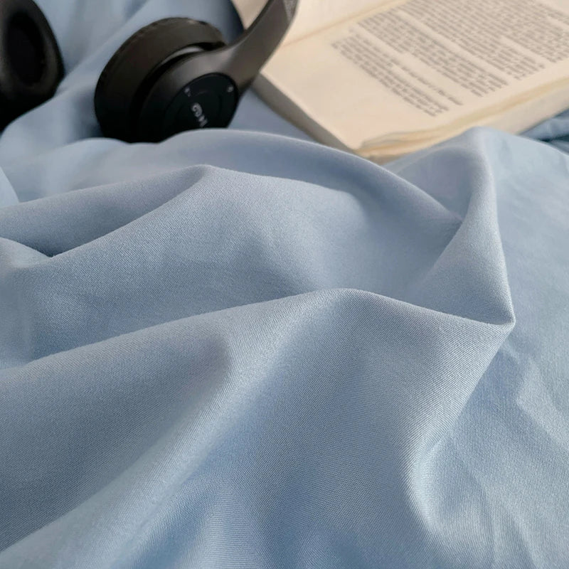 A close-up of a light blue linen fabric draped on a surface next to headphones and an open book.