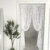 A sheer white floral embroidery curtain hanging in a doorway.