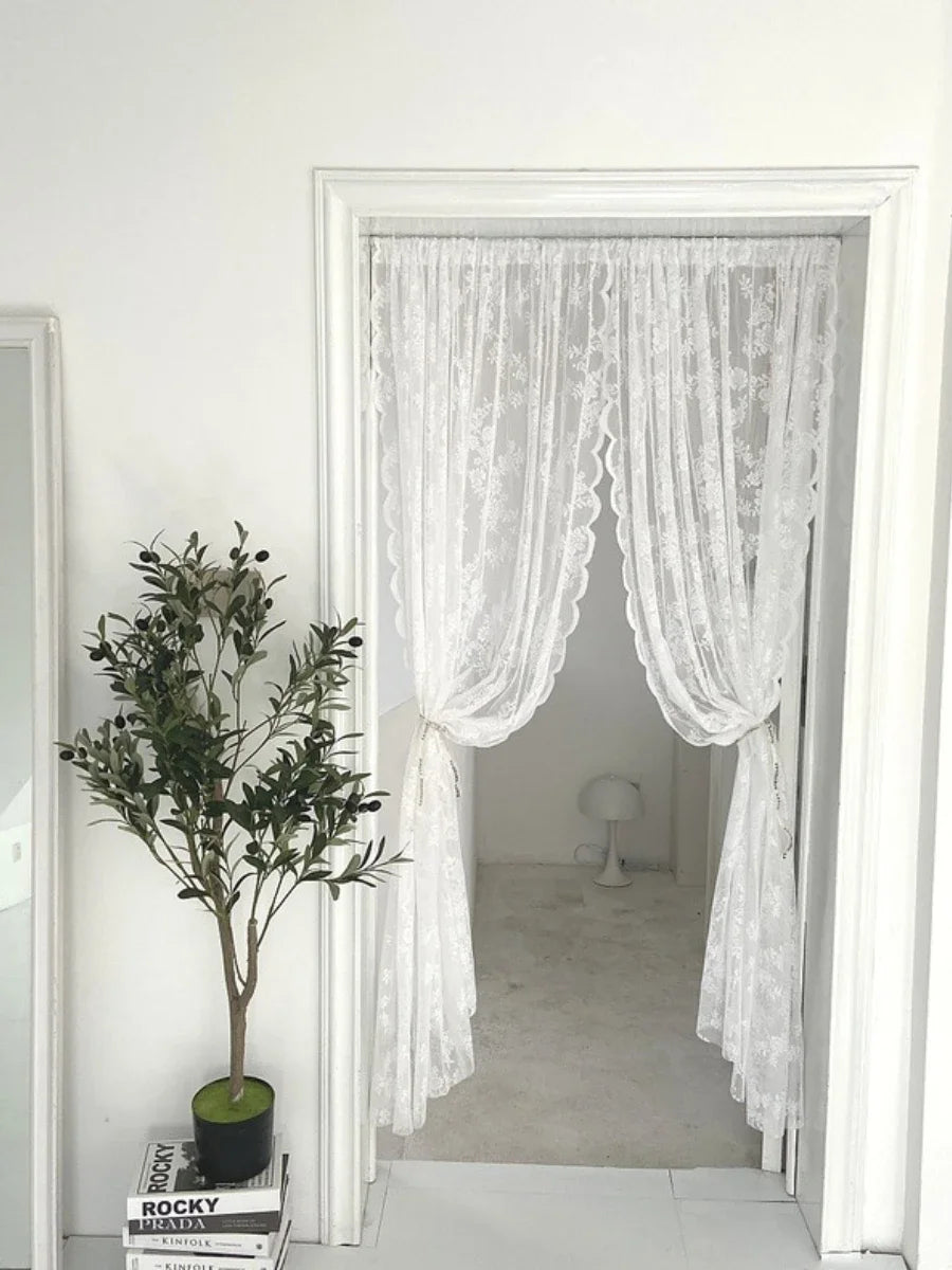 A sheer white floral embroidery curtain hanging in a doorway.