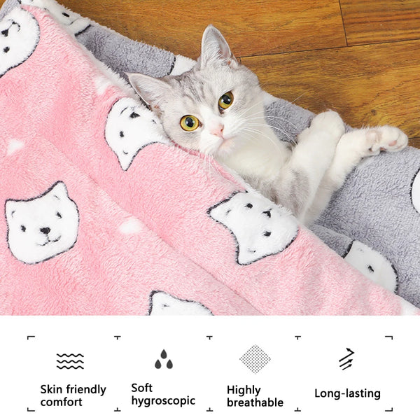 A fluffy gray cat is relaxing on a pink flannel pet mat.