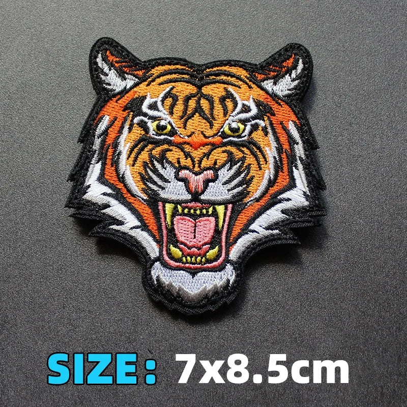 An embroidered patch featuring a fierce orange and black tiger face with white accents.