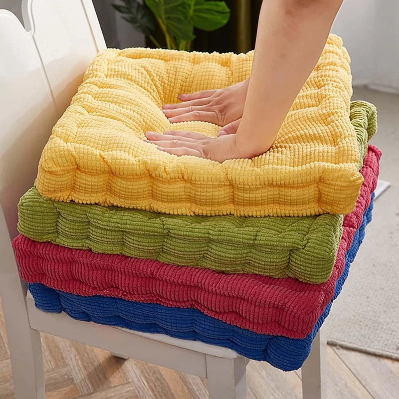 A stack of colorful tufted corduroy floor seat cushions in yellow, green, pink, and blue.