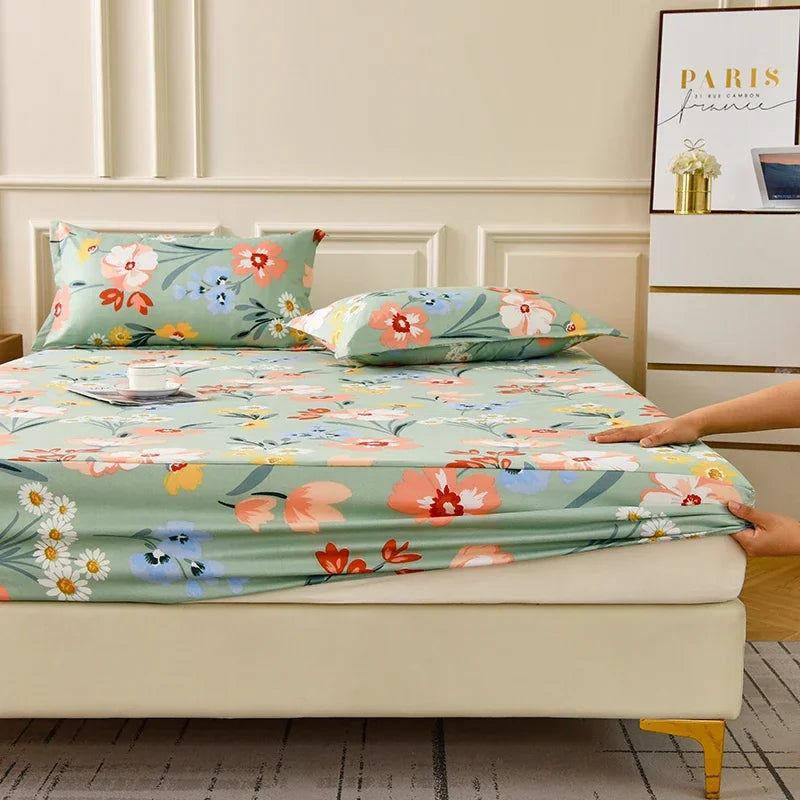 A floral fitted sheet set with green and pink flowers is displayed on a bed with white bedding and pillows.