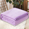 A purple cozy coral fleece throw blanket folded neatly on a white fluffy surface.