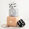 A stack of three plush dice cube cushions in white, gray, and beige with black polka dots.