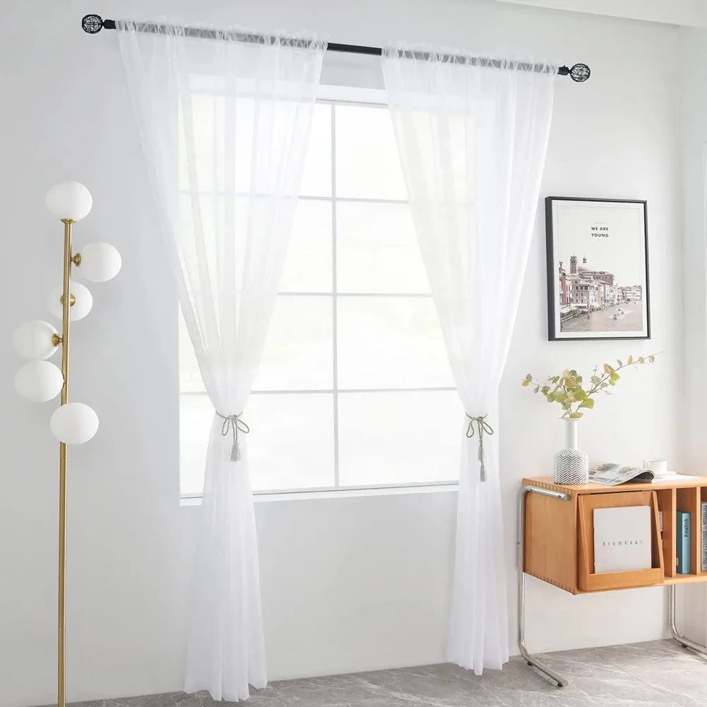 White semi-sheer tulle curtains with floral texture hanging in a bright room.
