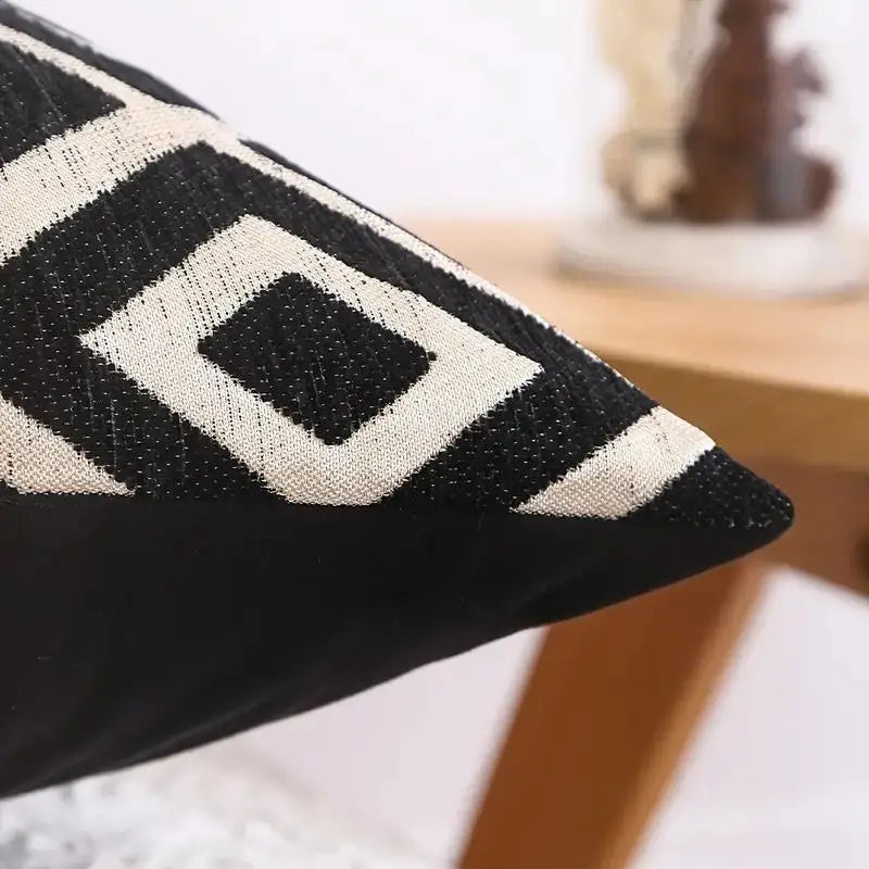 A close-up of a black and cream chenille jacquard throw pillowcase with a diamond pattern.