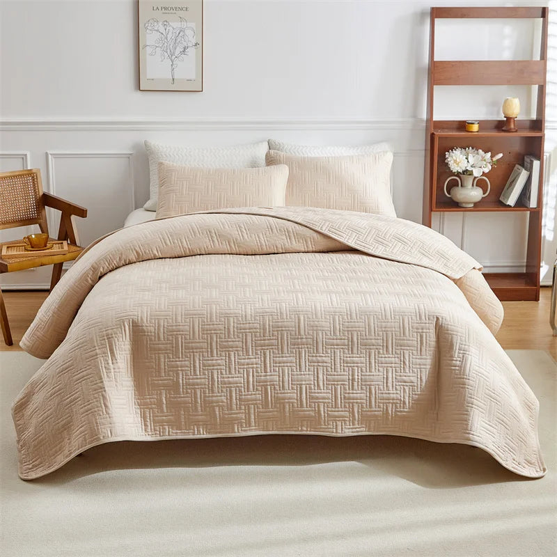 A beige quilted cotton bedspread set featuring a textured pattern is displayed on a bed.