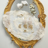 Elegant oval lace embroidered coaster set displayed in a gilded mirror frame.