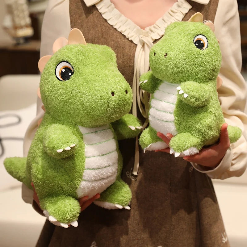 A person is holding two soft green dinosaur plush toys with white accents.