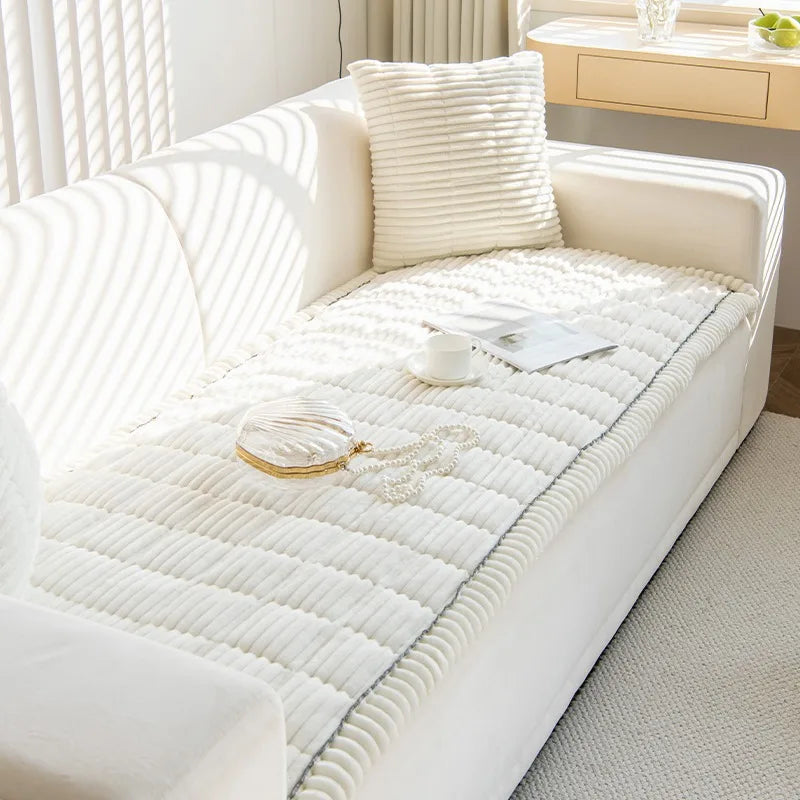 A white thick flannel sofa pad cover with vertical stitching is displayed on a light-colored sofa.