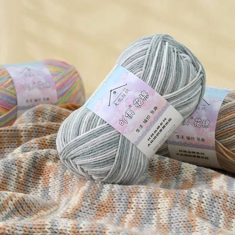 A ball of gray yarn is shown next to a knitted fabric featuring multicolored stripes.