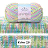 A ball of multicolored 4-ply cotton knit yarn with a gradient pattern displayed on a green knitted fabric.