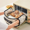 A person is using floral patterned heat-resistant oven mitts to handle baked goods inside an oven.