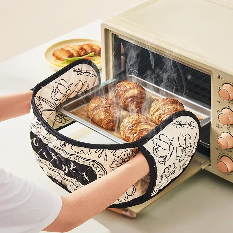 A person is using floral patterned heat-resistant oven mitts to handle baked goods inside an oven.