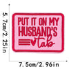 Pink embroidered iron-on clothing patch with red text that reads Put it on my husband's tab