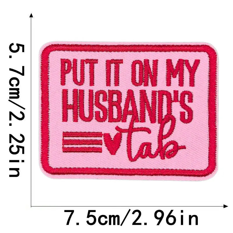 Pink embroidered iron-on clothing patch with red text that reads Put it on my husband's tab