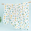 White muslin swaddle blanket with a repeating pattern of colorful cacti and succulents hanging on a wooden rod.