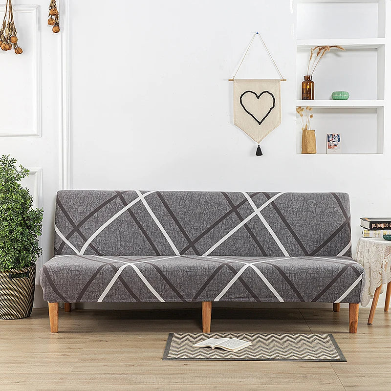 A gray geometric print spandex slipcover on a sofa bed with a white accent, displayed in a bright room.