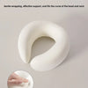 A white U-shaped memory foam neck pillow is shown, with a hand demonstrating its gentle wrapping and support.