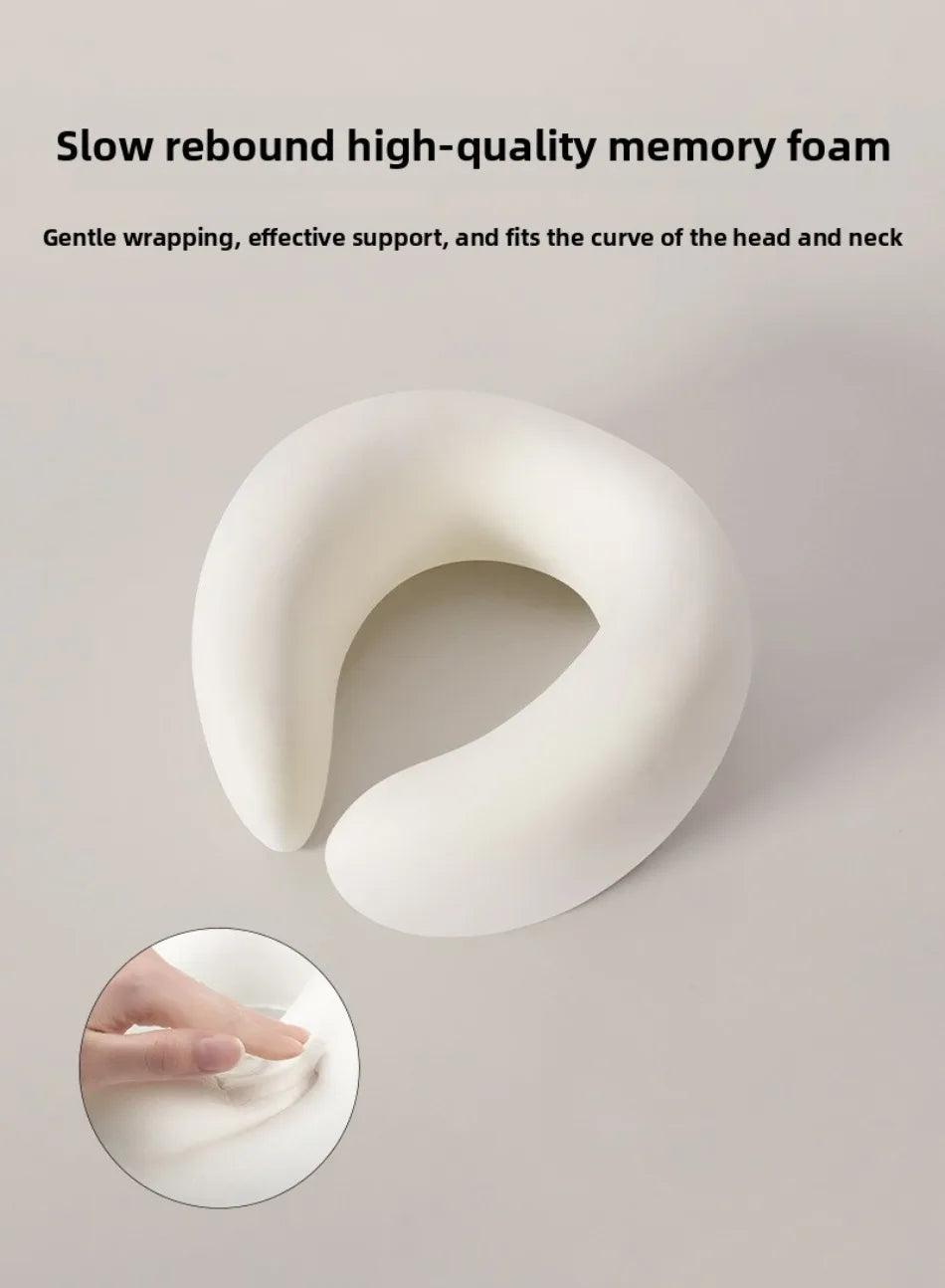 A white U-shaped memory foam neck pillow is shown, with a hand demonstrating its gentle wrapping and support.