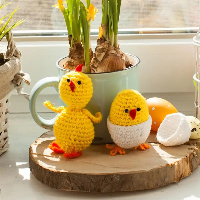 A yellow knitted chick figurine sits in front of a pot containing several kn rolled onions.