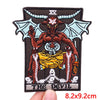 A dark embroidery patch featuring a demonic face with horns and bat wings, set against a black background.