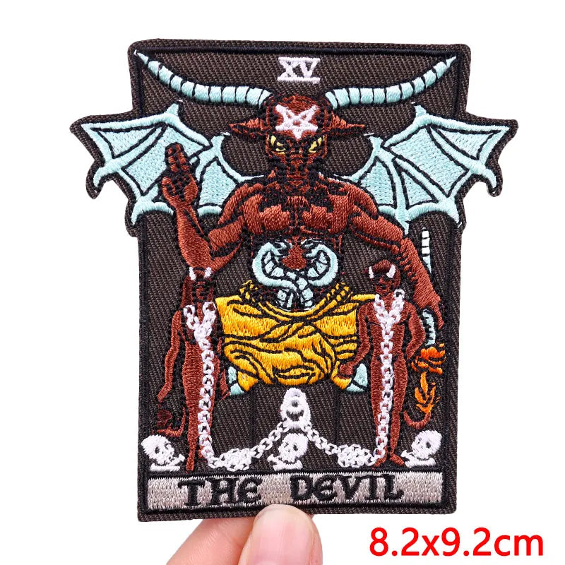 A dark embroidery patch featuring a demonic face with horns and bat wings, set against a black background.