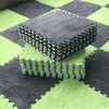 A stack of gray interlocking puzzle rug mats on a green and gray checkered floor.